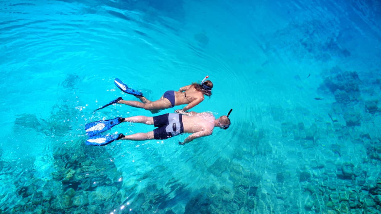 Photo of a couple snorkeling on the crystal clear waters of Navarino sea.